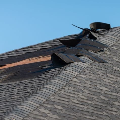 Close-up of a curled and weathered asphalt shingle edge