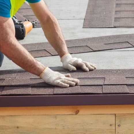 Close-up of hands installing asphalt shingles